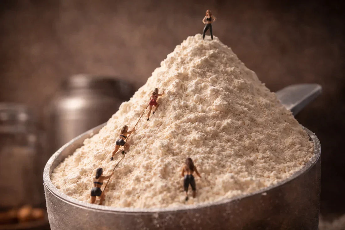 miniature wooden figurines of women climbing a gigantic mountain of protein powder as a conceptual representation of the best protein powders for muscle gain in women